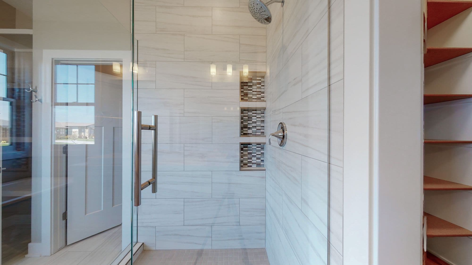 Modern bathroom featuring a glass shower with a tile surround and built-in shelves, alongside a bright and minimalist interior with open shelving. The neutral color palette and clean lines create a spa-like atmosphere.