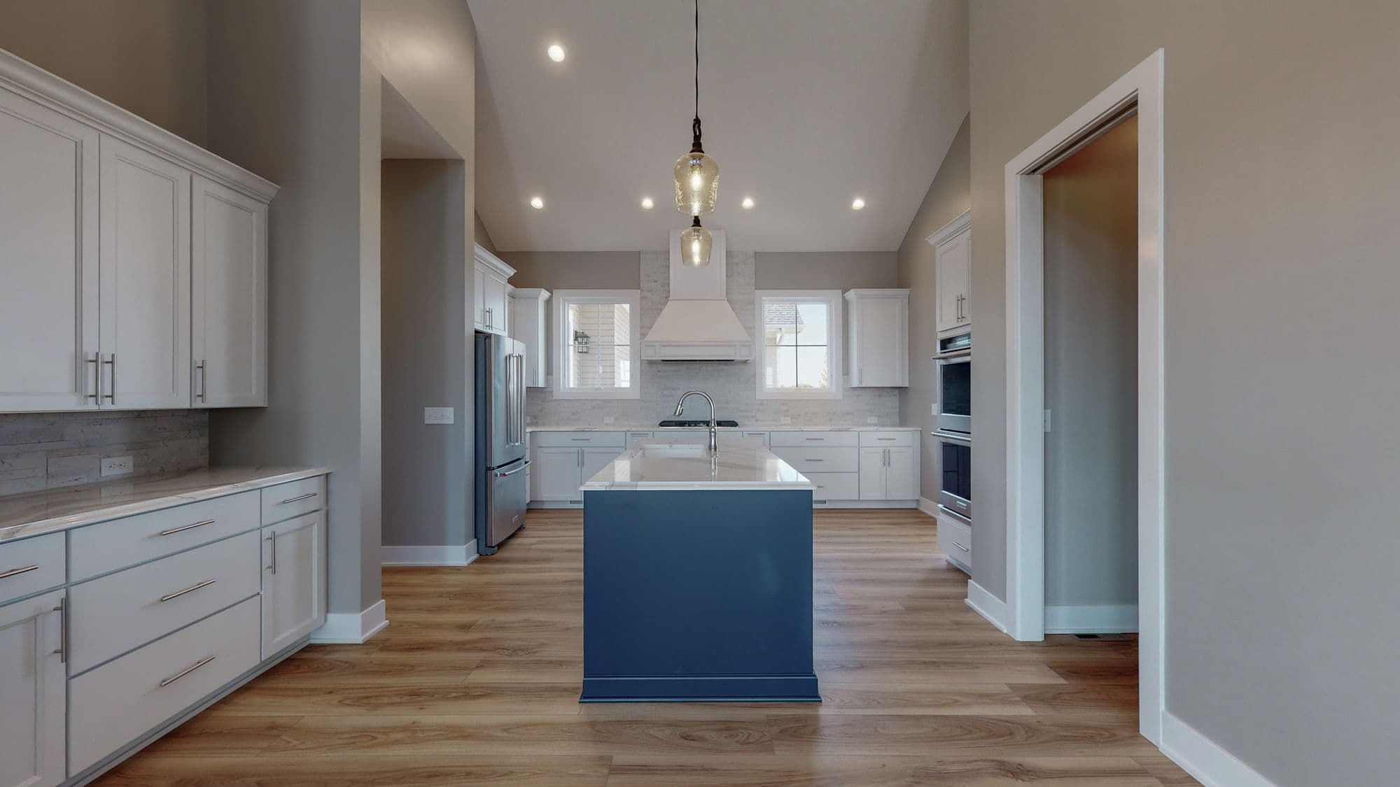 Spacious kitchen with vaulted ceilings, recessed lighting, and a center island. Features white cabinetry and stainless steel appliances.