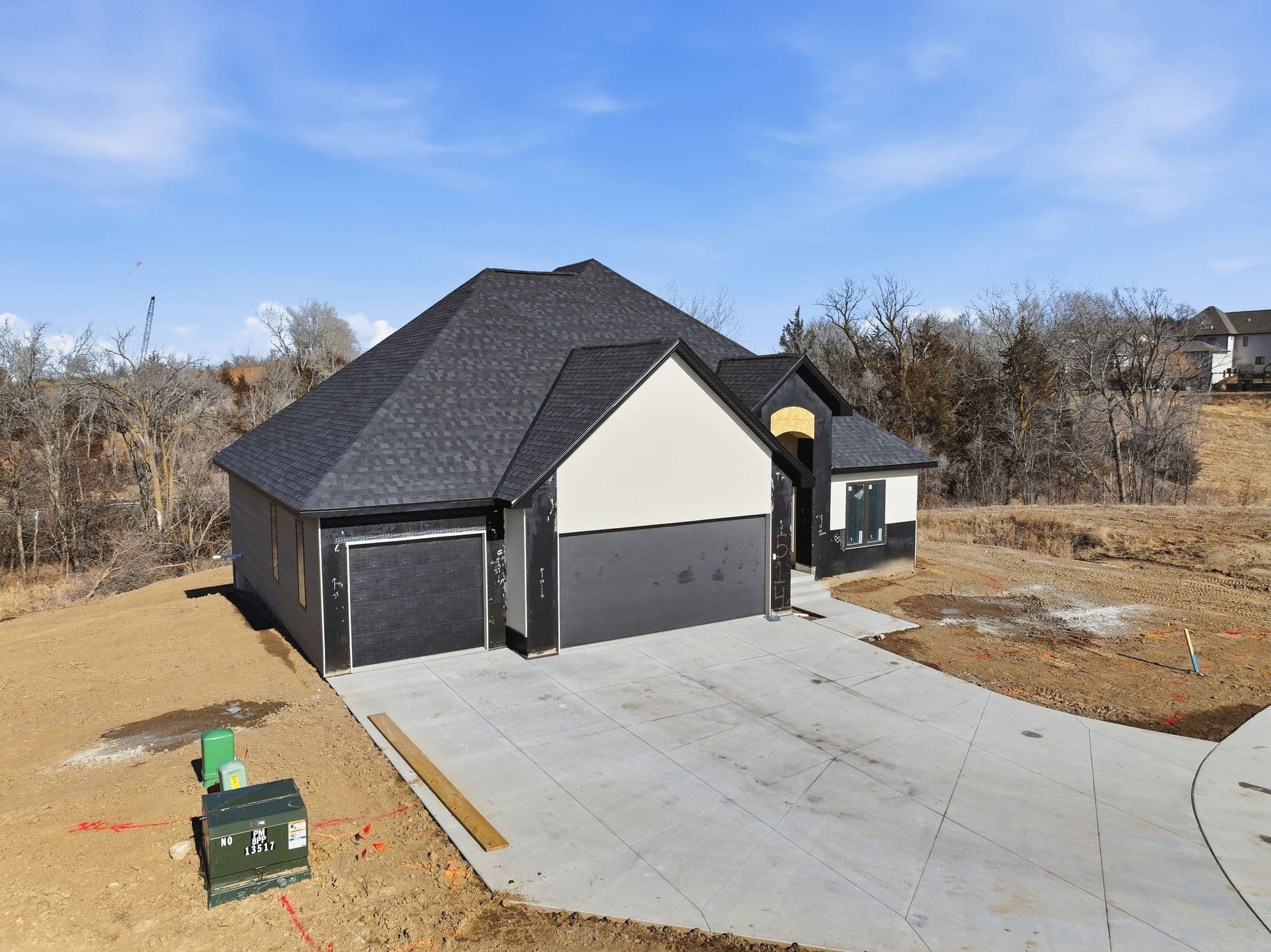 New construction home featuring a dark gray exterior with a light cream colored accent wall above the garage. A concrete driveway leads to the attached garage, and the yard is yet to be landscaped.