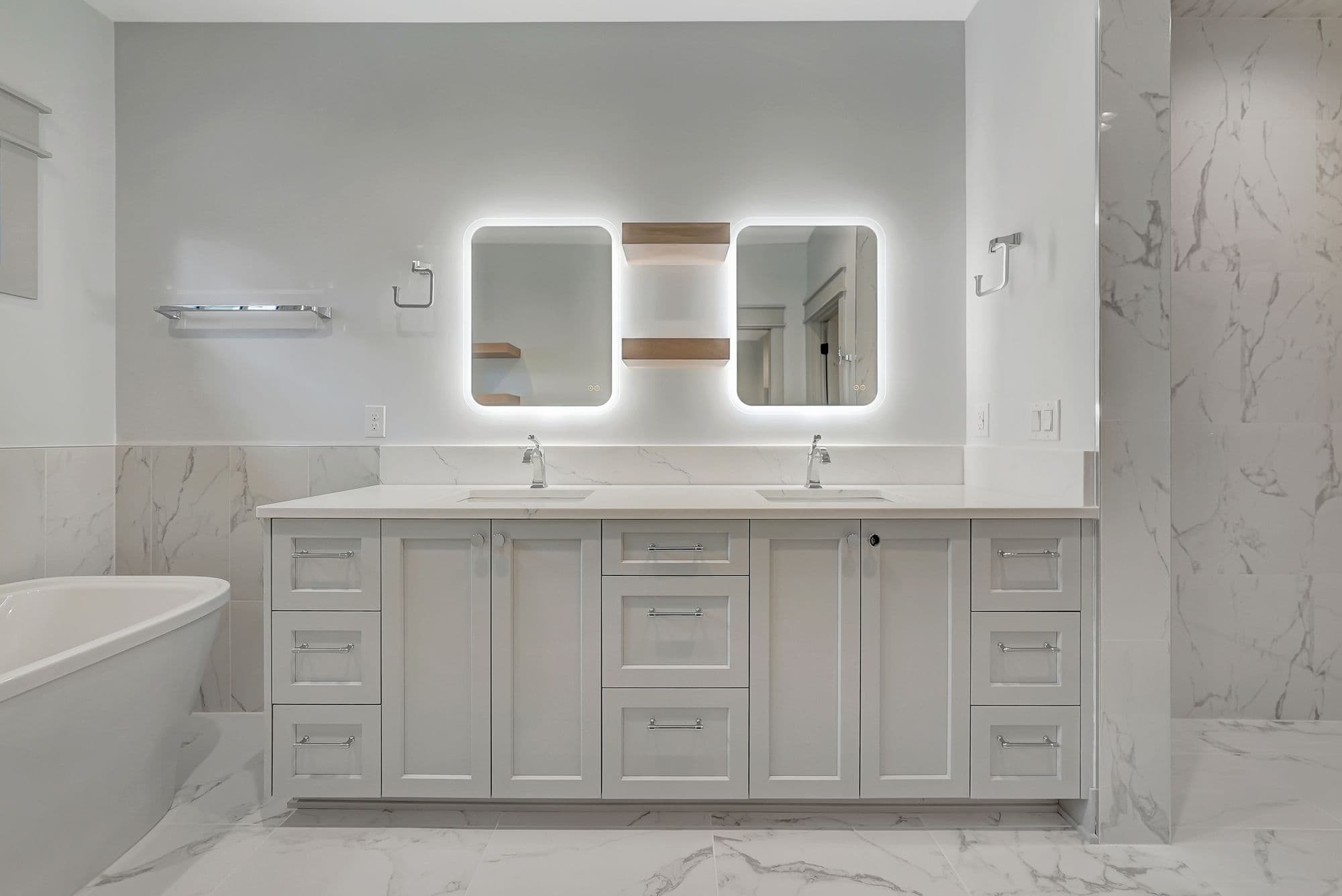 Modern bathroom features a double vanity with white cabinets and countertops, complemented by illuminated square mirrors with open shelving. Marble-patterned tile on the floor and walls adds a luxurious touch.
