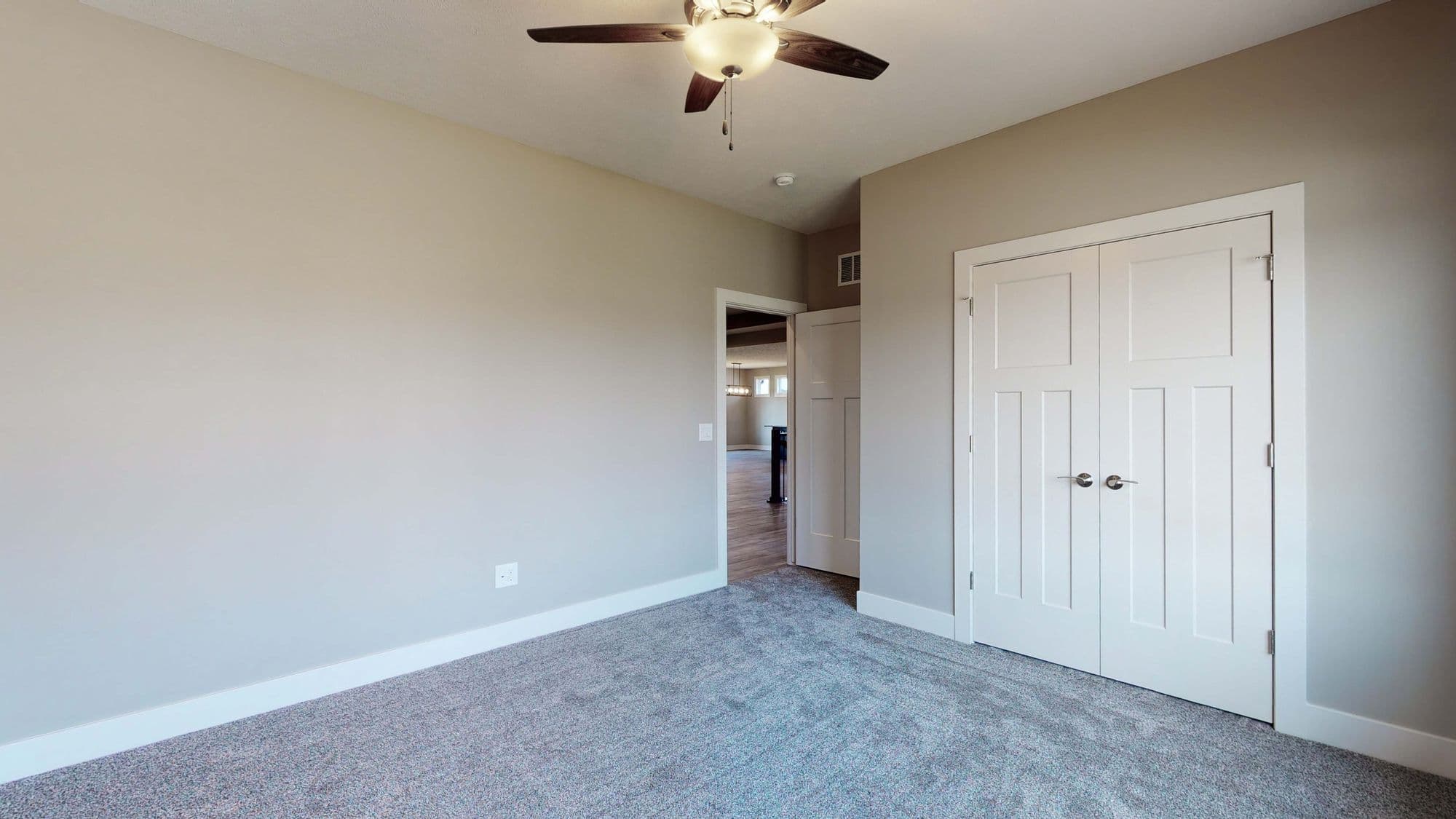 Bedroom features neutral wall color, gray carpeting, and a white closet. A ceiling fan with a light is visible overhead.