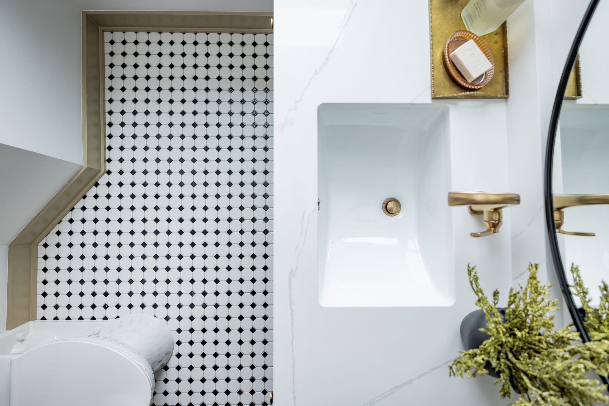 Modern bathroom with white marble countertop and white square sink. Features black and white patterned tile backsplash and gold hardware.
